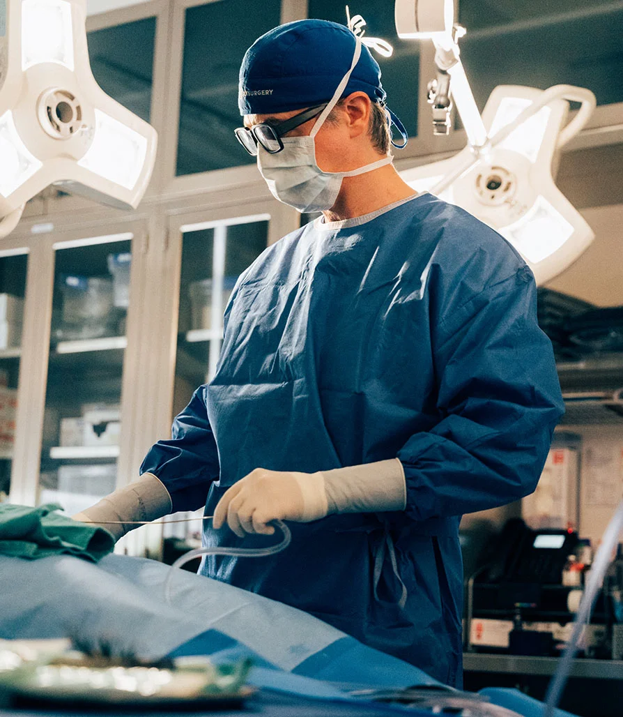 Dr. Jugenberg, in full surgical attire, performing a precision liposuction procedure in a state-of-the-art operating room.